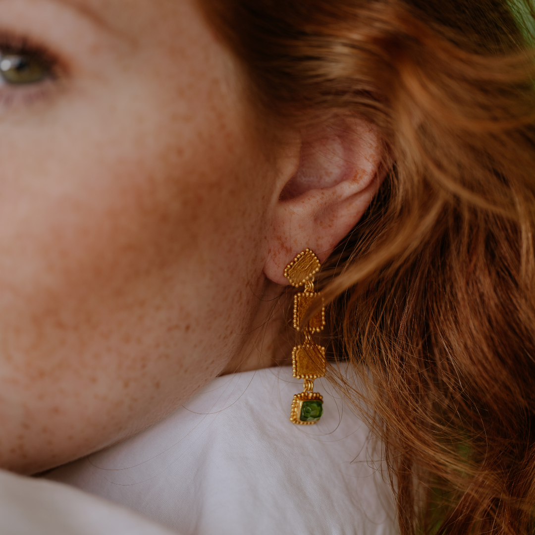 Experience luxury with these earrings, crafted with rich gold hues and adorned with unusual green tourmaline gemstones.