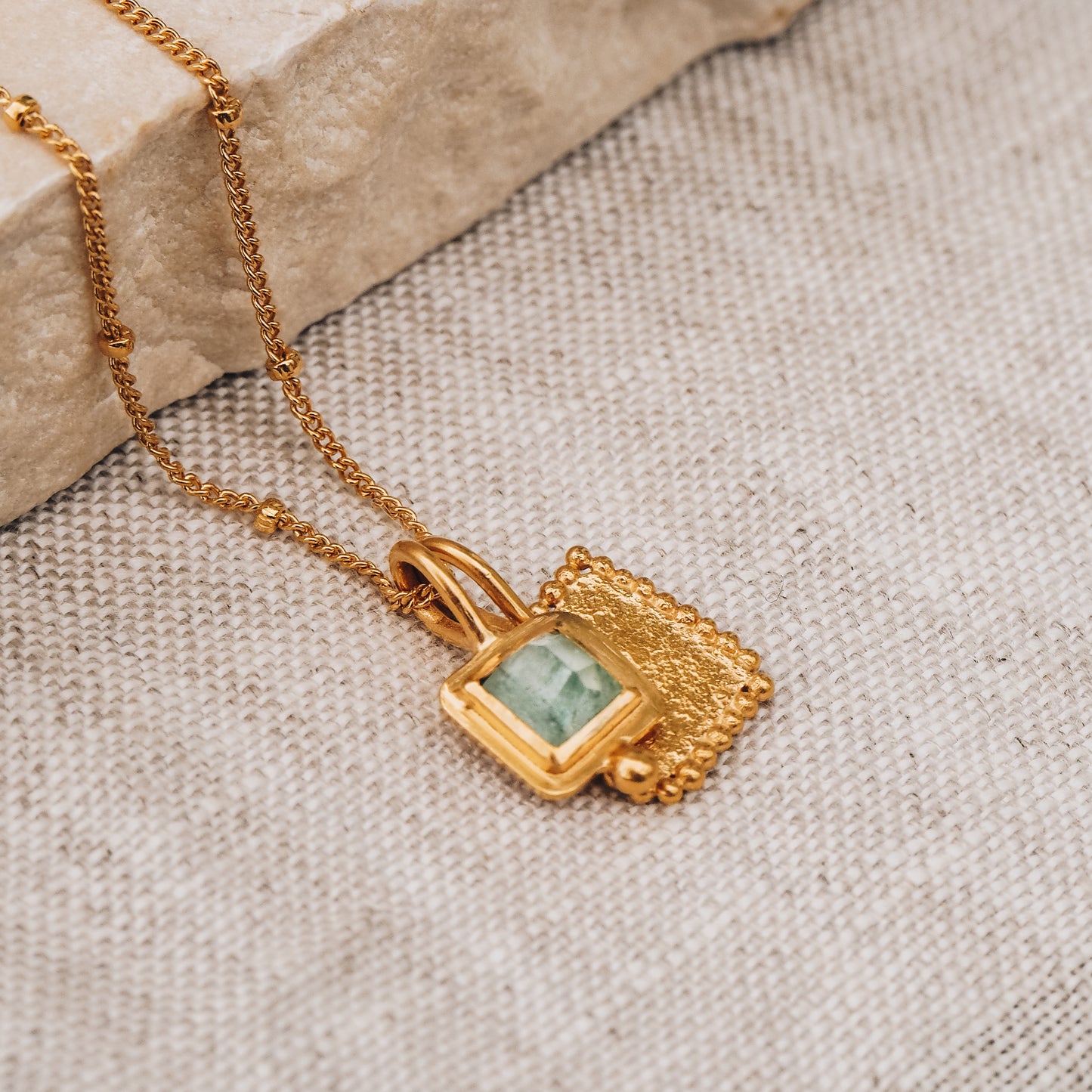 Square gold pendant with a breathtaking blue rose cut tourmaline gemstone and intricate granulation work, elegantly hanging from a fine satellite chain.