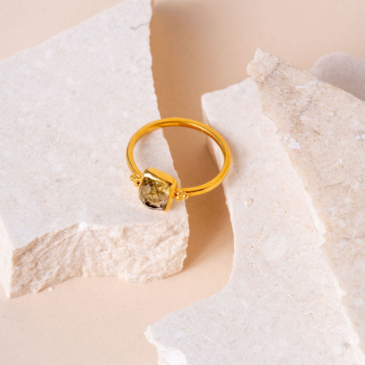 Image of a artisan crafted gold ring with intricate granulation, accentuating the beauty of an organic olive-colored gemstone.