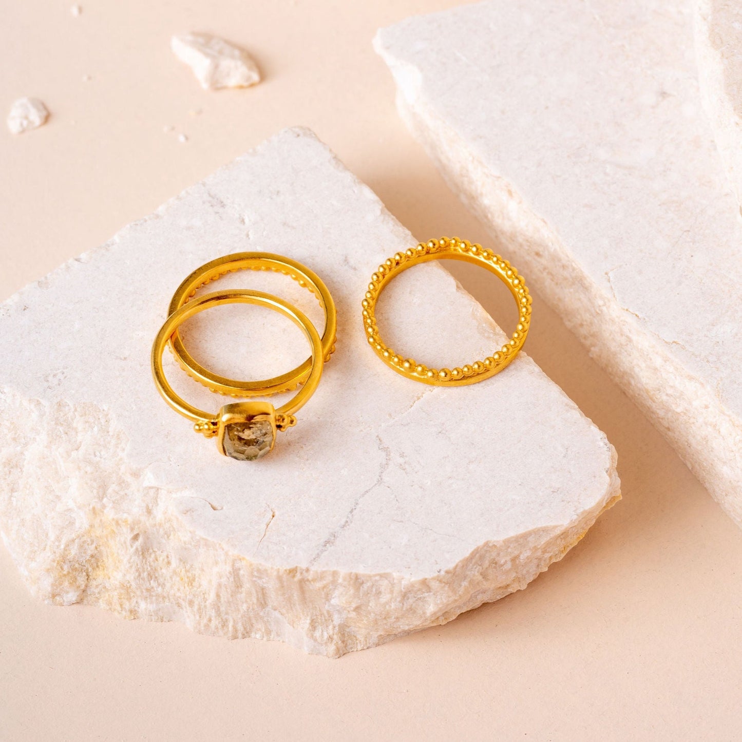 Group of a handcrafted gold rings, featuring fine granulation work and an alluring olive-colored hand-cut gemstone