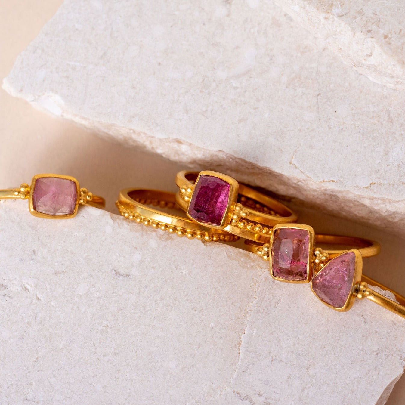 Group of artisan gold rings, each uniquely designed with delicate granulation and set with hand cut pink tourmaline for added elegance.