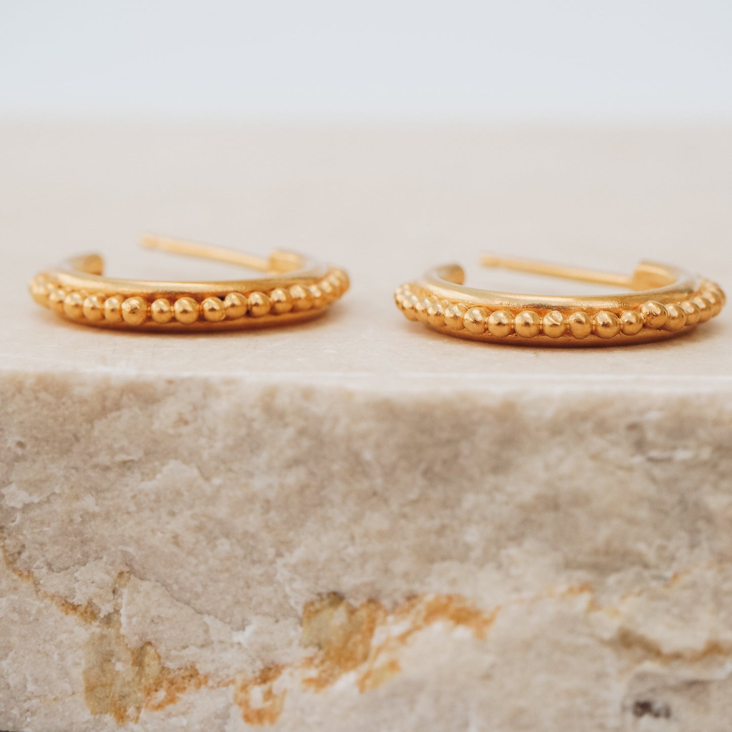 Gold stud hoop earrings featuring intricate granulation, a nod to ancient beauty and craftsmanship.