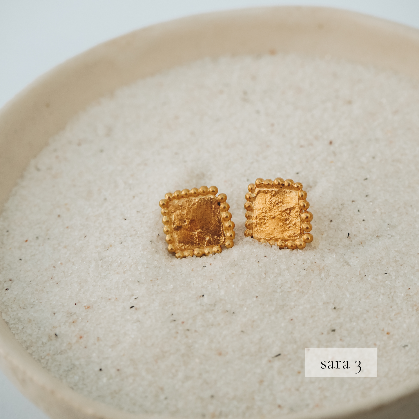 Small square stud earrings in lustrous gold, adorned with intricate granulation