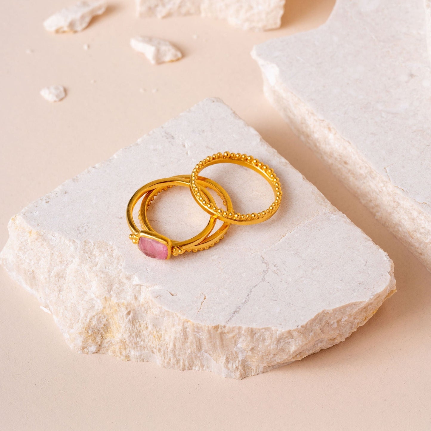 Artisan gold ring with intricate detailing and a small, hand-cut light pink square tourmaline.
