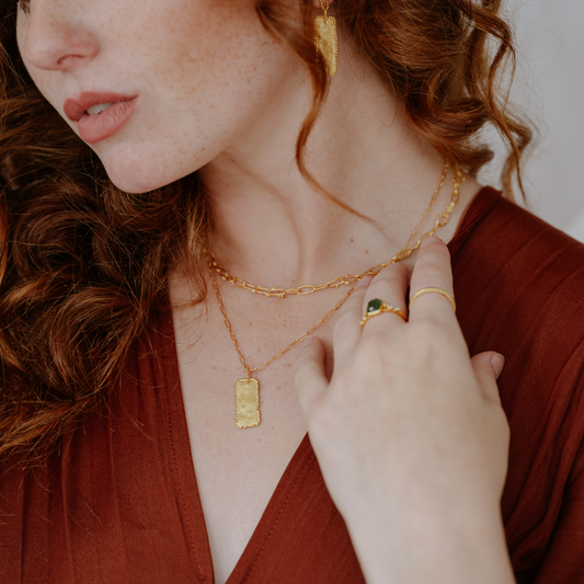 Elevate your ensemble with this timeless necklace boasting a rectangular pendant in rich gold colour and organic textures.