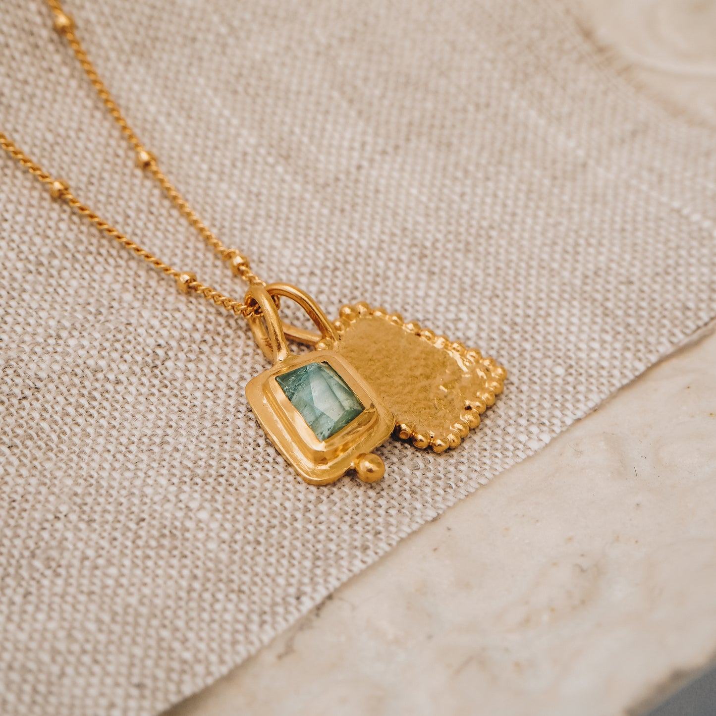 Elegant square gold pendant featuring a stunning blue rose cut tourmaline gemstone and delicate granulation, suspended from a fine satellite chain.