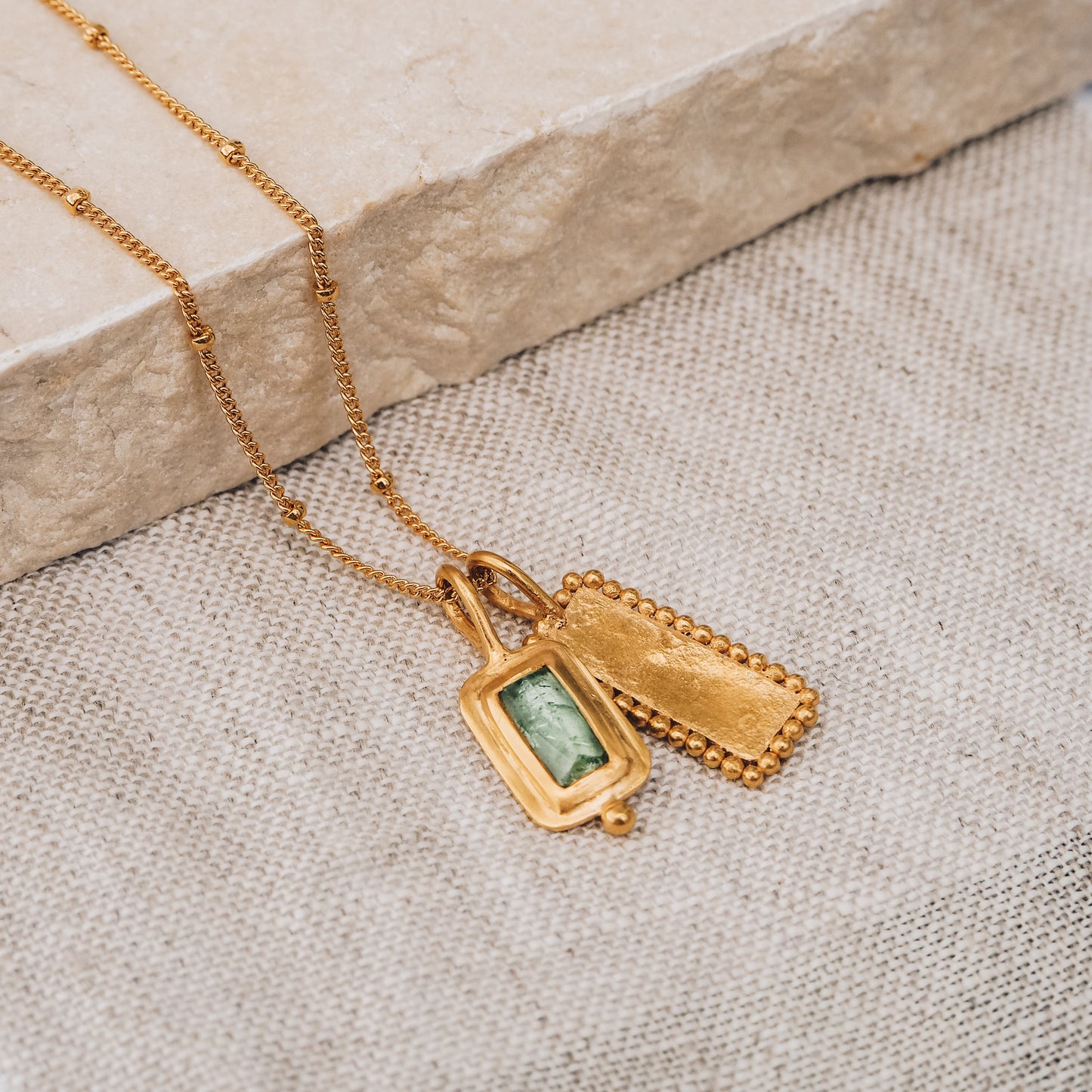 Handmade square gold pendant featuring a captivating blue rose cut tourmaline gemstone and meticulous granulation detail, suspended from a delicate satellite chain.