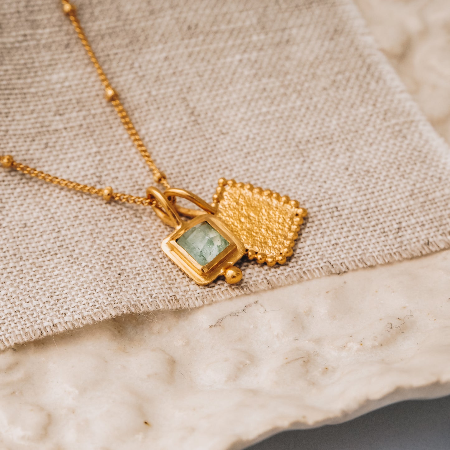 Handcrafted square gold pendant featuring a captivating blue rose cut tourmaline gemstone and meticulous granulation work, elegantly suspended from a satellite chain.