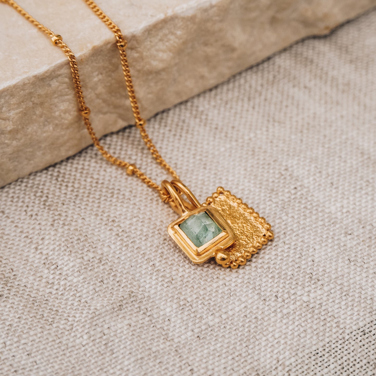 Artisan-crafted square gold pendant showcasing a breathtaking blue rose cut tourmaline gemstone and intricate granulation, suspended from a delicate satellite chain.