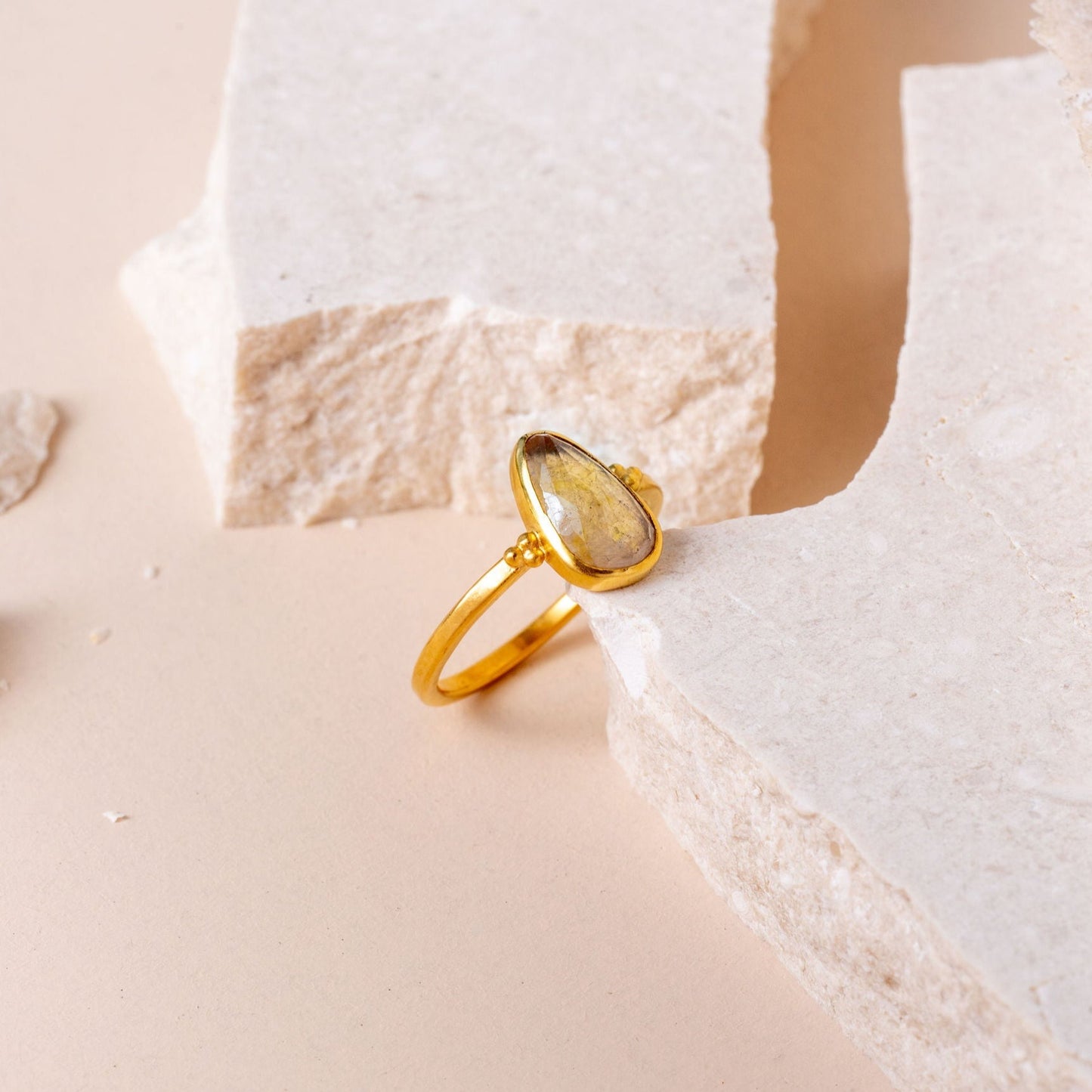 Handmade gold ring showcasing a delicate teardrop-shaped yellow sapphire and exquisite granulation work.