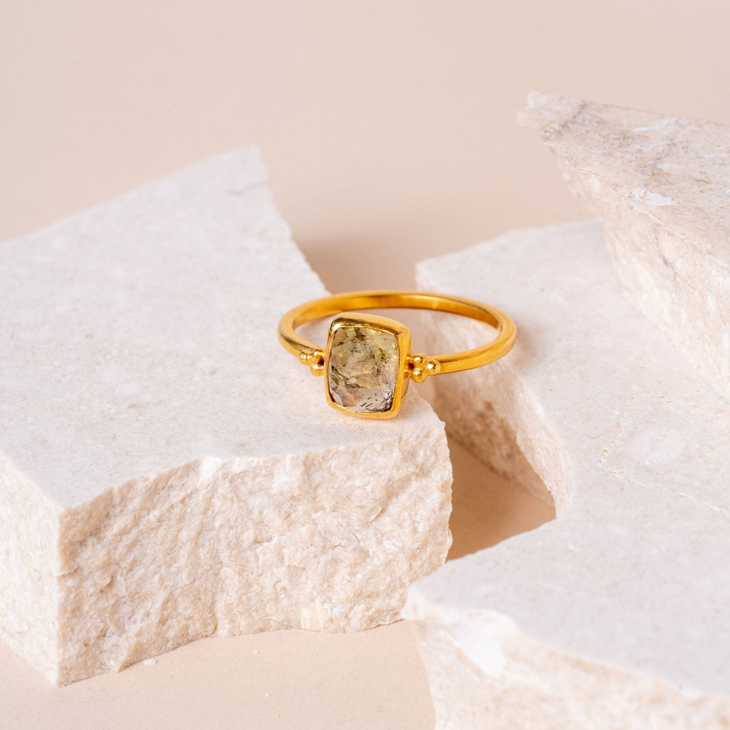 A rich gold ring featuring delicate granulation, elegantly framing a hand-cut olive-coloured natural gemstone.