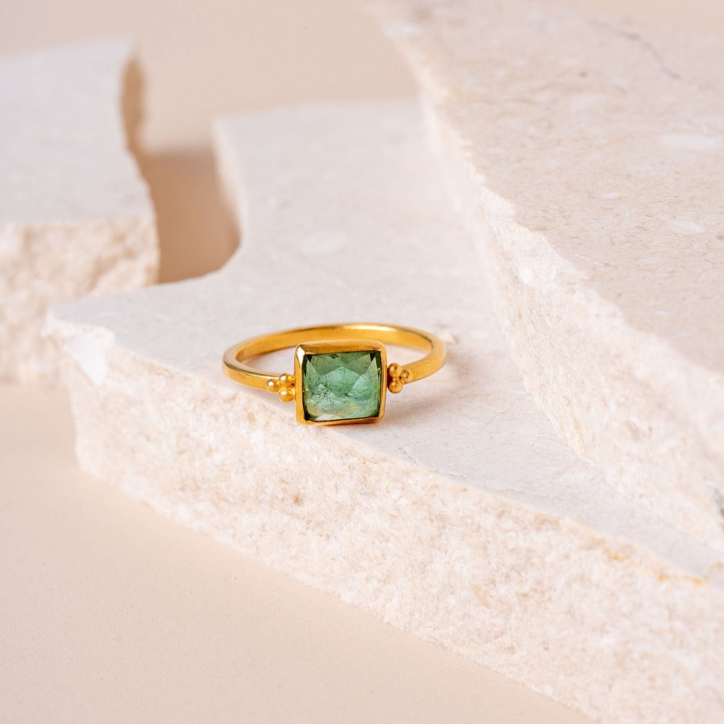 Intricately designed gold ring, adorned with fine granulation and centered around a vibrant green square tourmaline.
