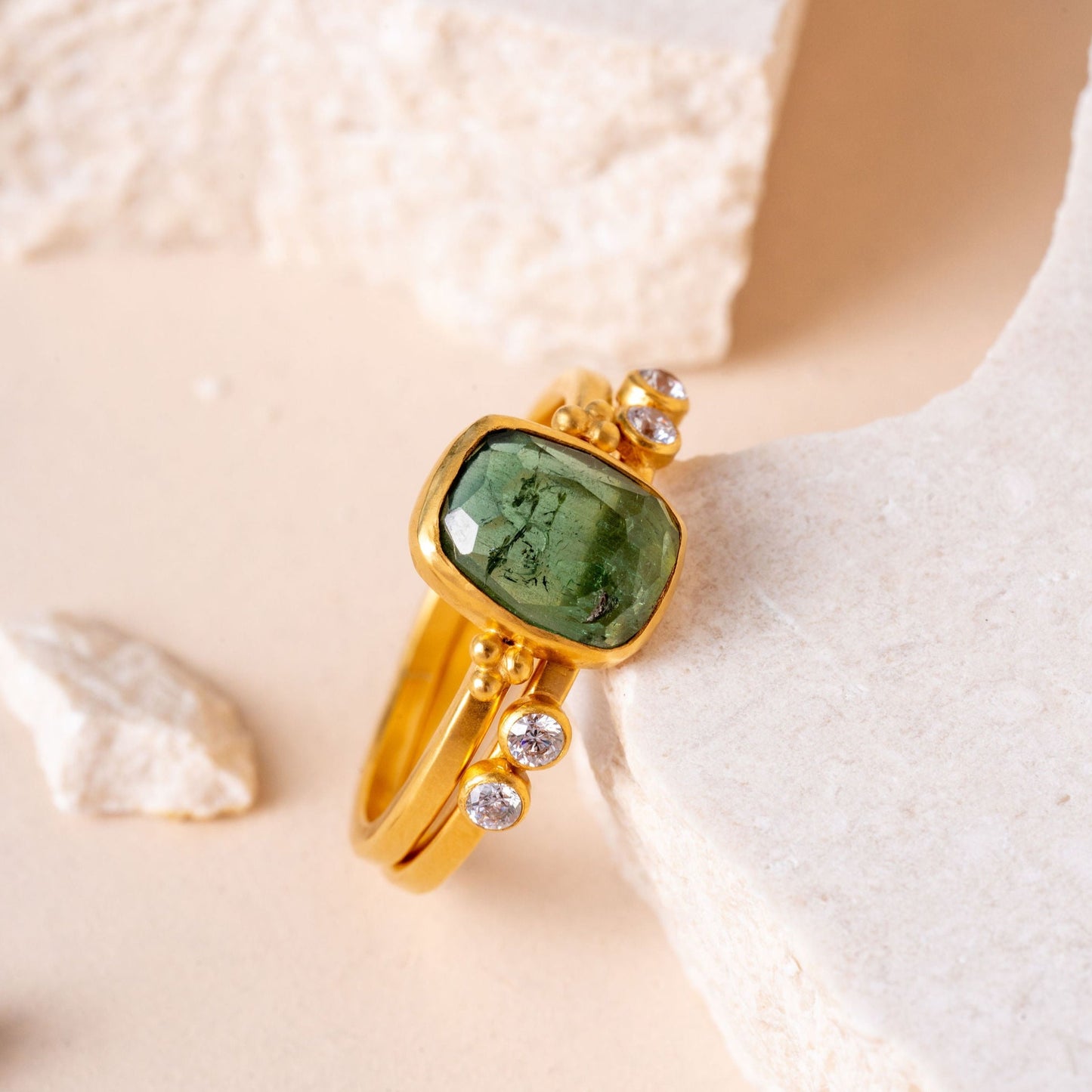 Intricately designed gold rings in a harmonious group, highlighting delicate granulation and the enchanting presence of green tourmaline gemstones
