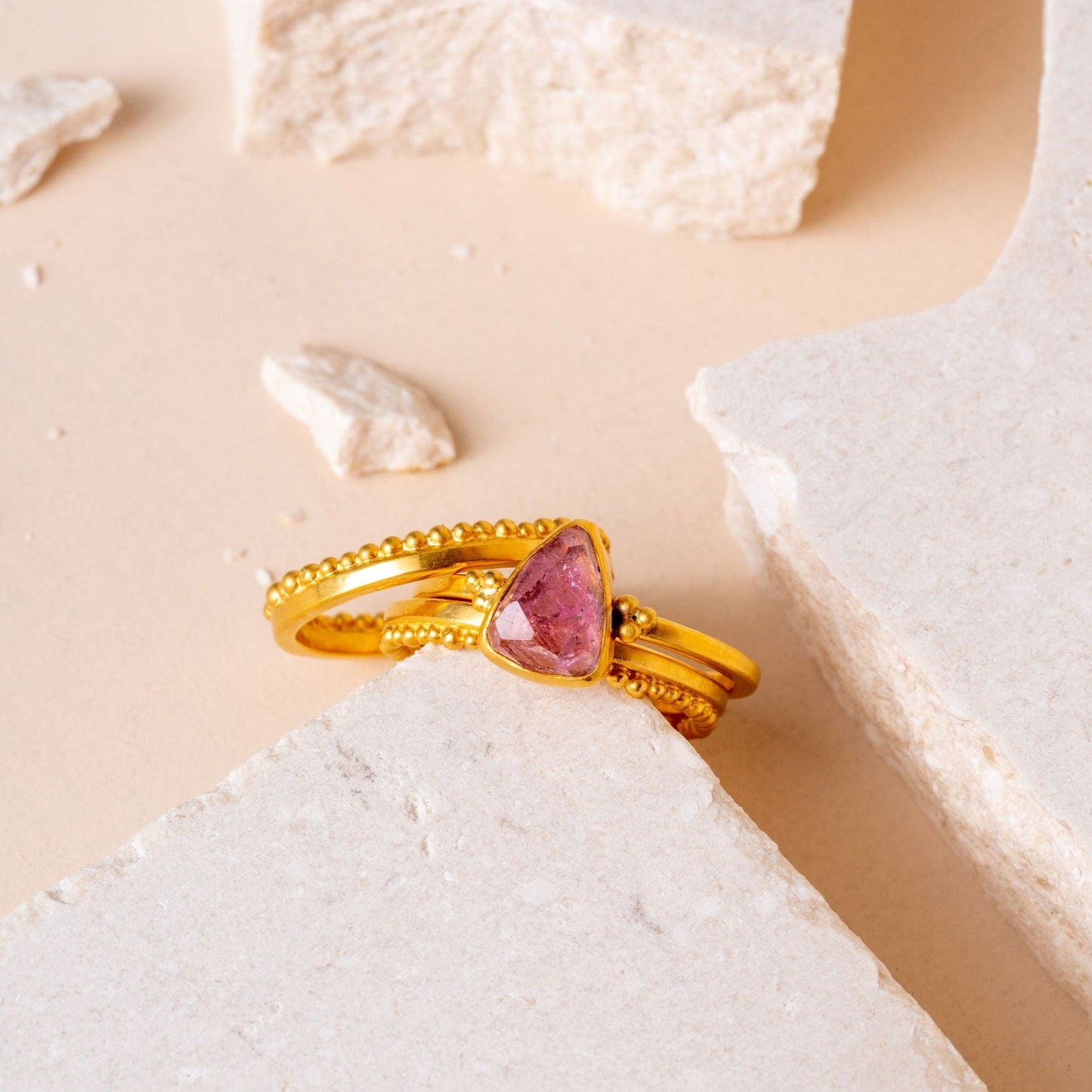 A collection of gold rings, one adorned with a lovely pink tourmaline gem and delicate granulation showing exquisite craftsmanship.