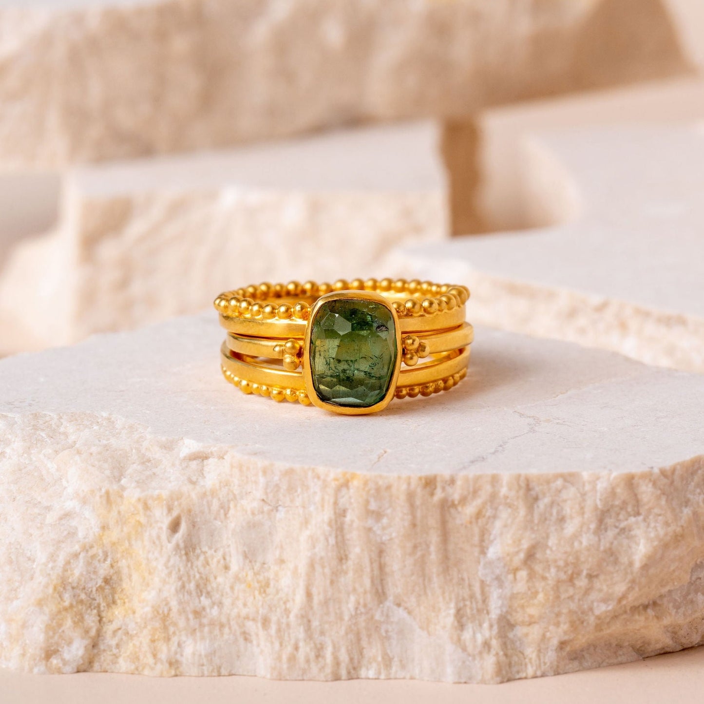 A collection of elegant gold rings, united by their masterful granulation craftsmanship and enhanced by vibrant green tourmaline gemstones