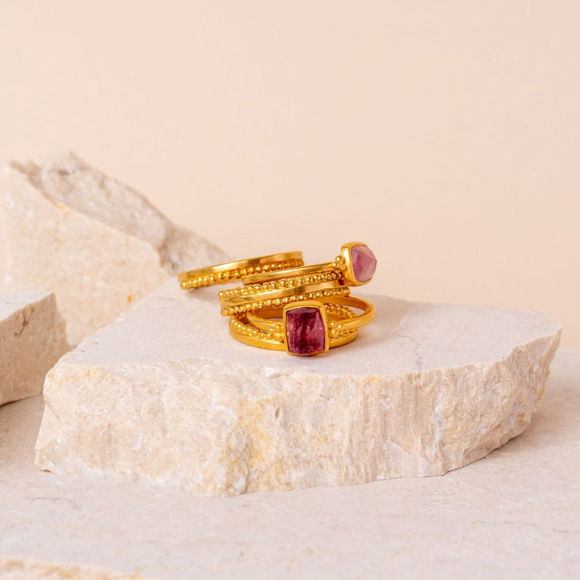 Distinctive gold ring stack adorned with vibrant pink rose-cut tourmaline gemstones and delicate granulation detailing.