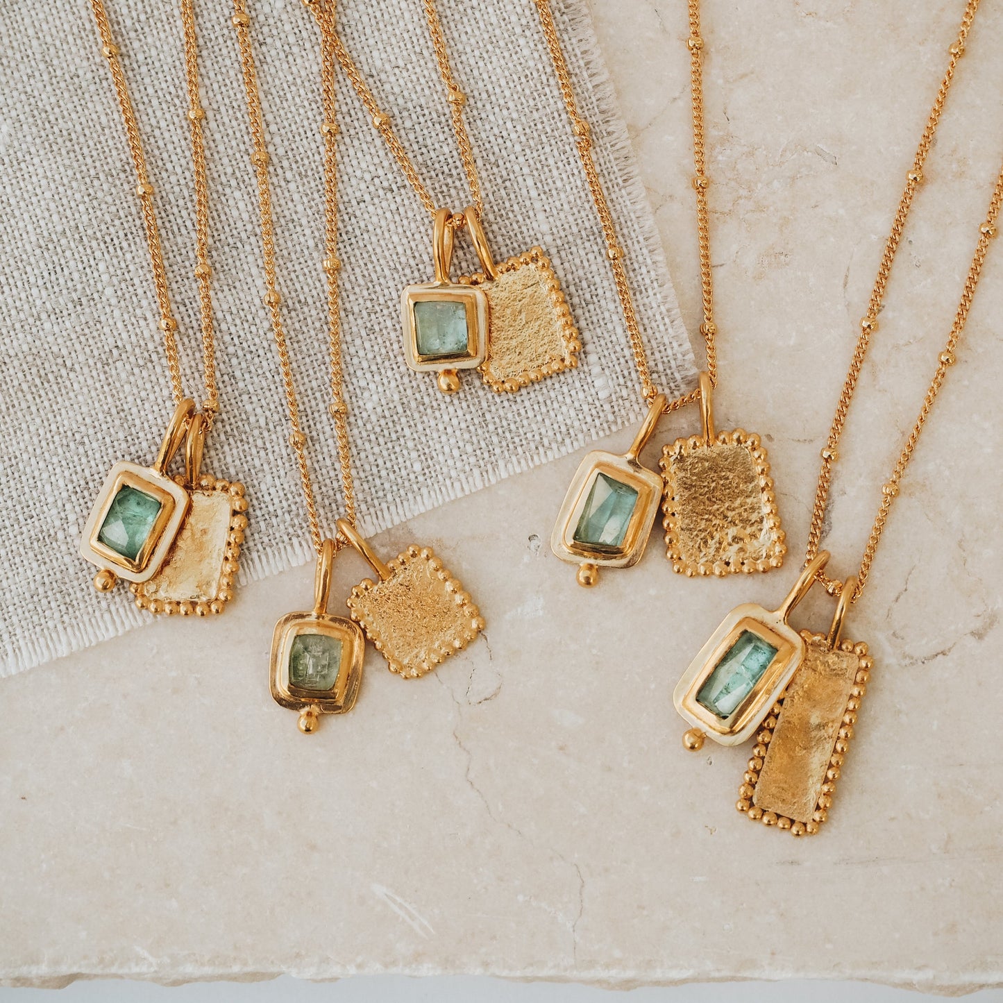 A group of hand crafted necklaces in gold with blue geometric gemstones