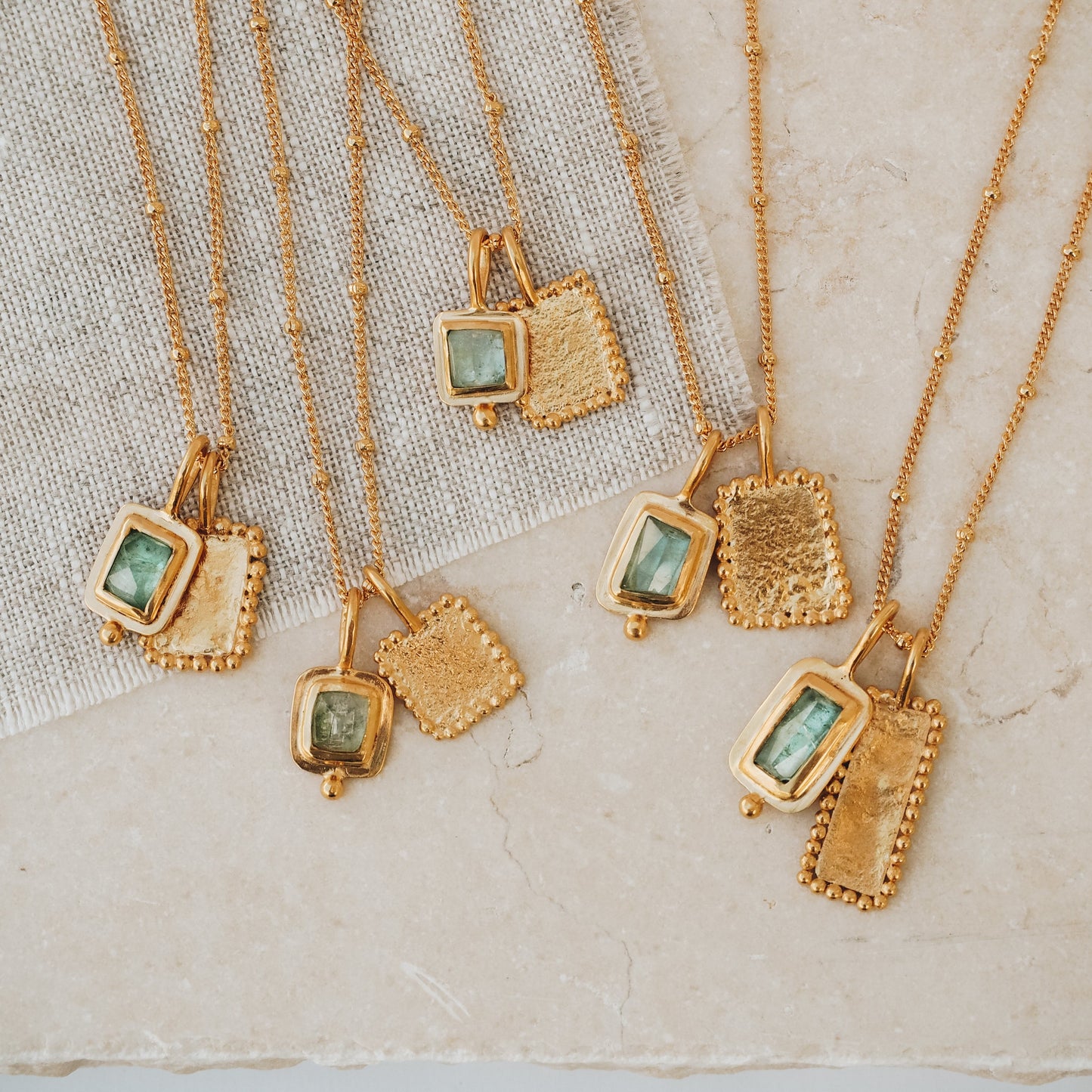 Exquisite square gold pendant featuring a captivating blue rose cut tourmaline gemstone and intricate granulation detail, gracefully suspended from a fine satellite chain.