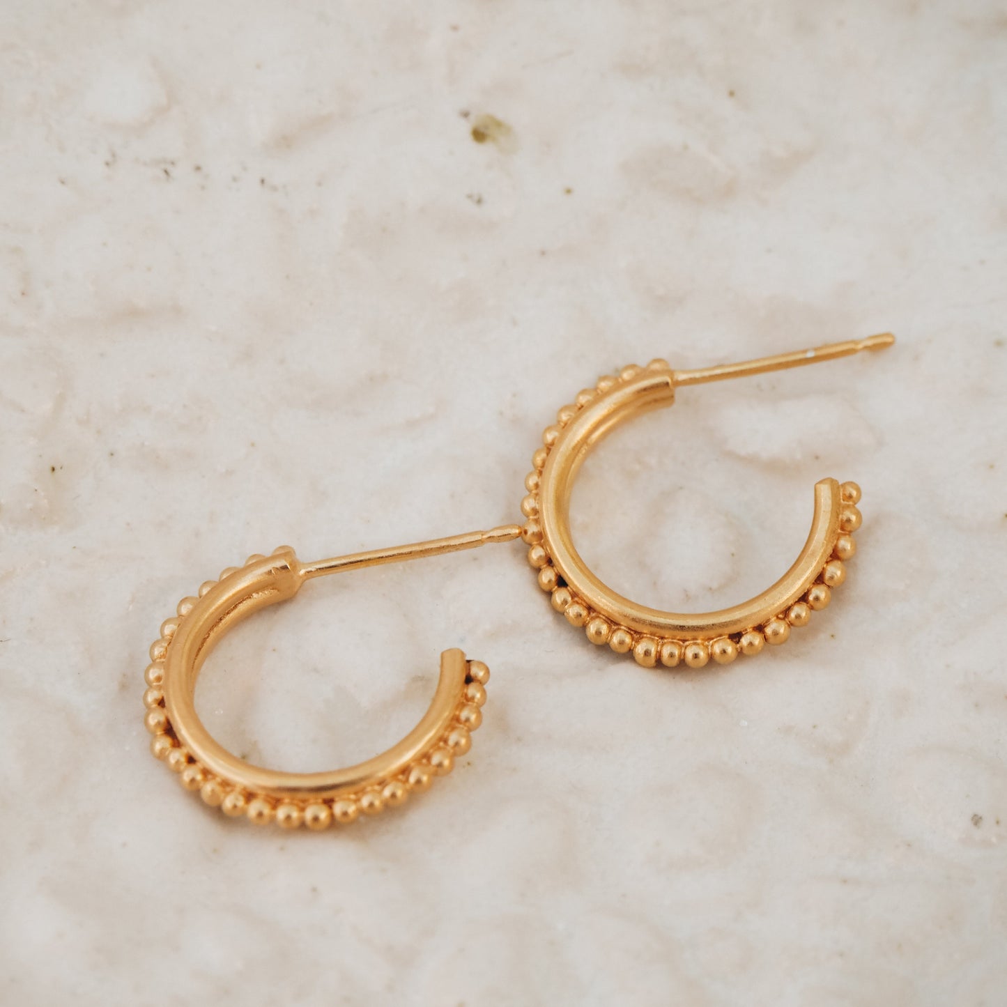 Ancient-inspired gold stud hoop earrings with delicate granulation detailing, a timeless statement.