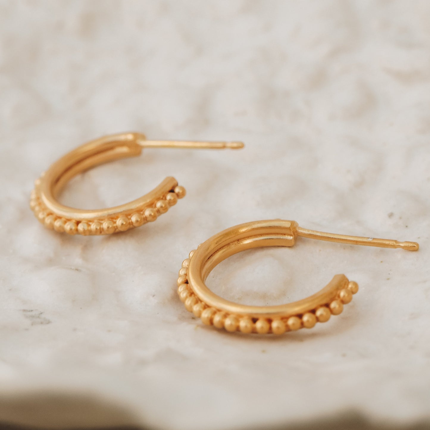 Delicate gold stud hoop earrings with granulation detailing, inspired by ancient jewelry traditions.