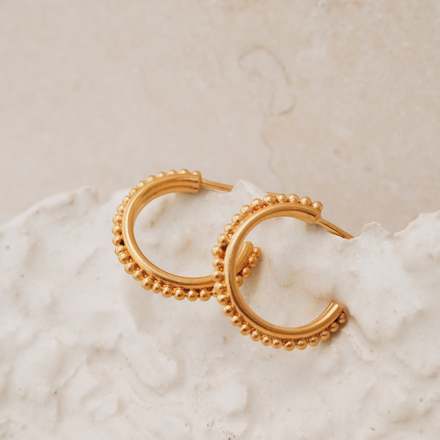 Handcrafted gold stud hoop earrings with delicate granulation, reminiscent of ancient treasures.