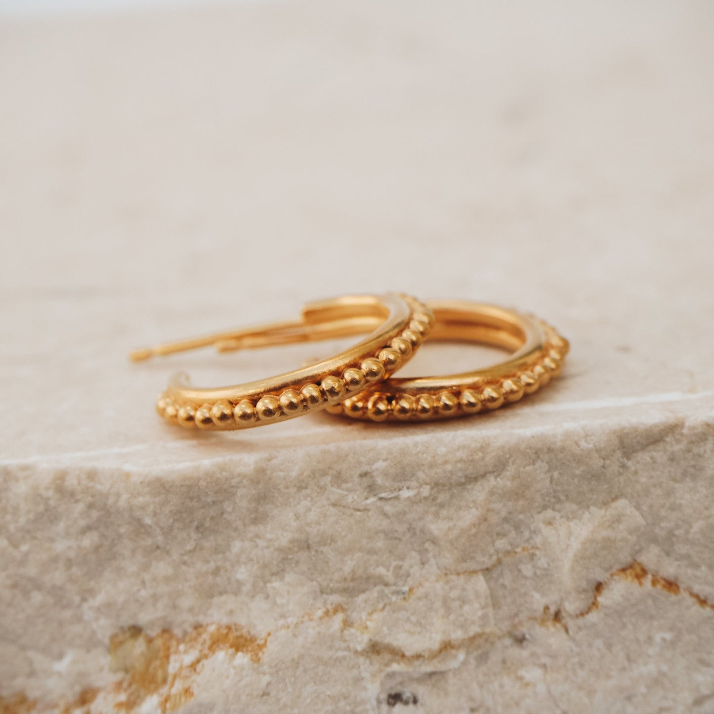 Ancient-inspired gold stud hoop earrings showcasing intricate granulation work for a unique aesthetic.