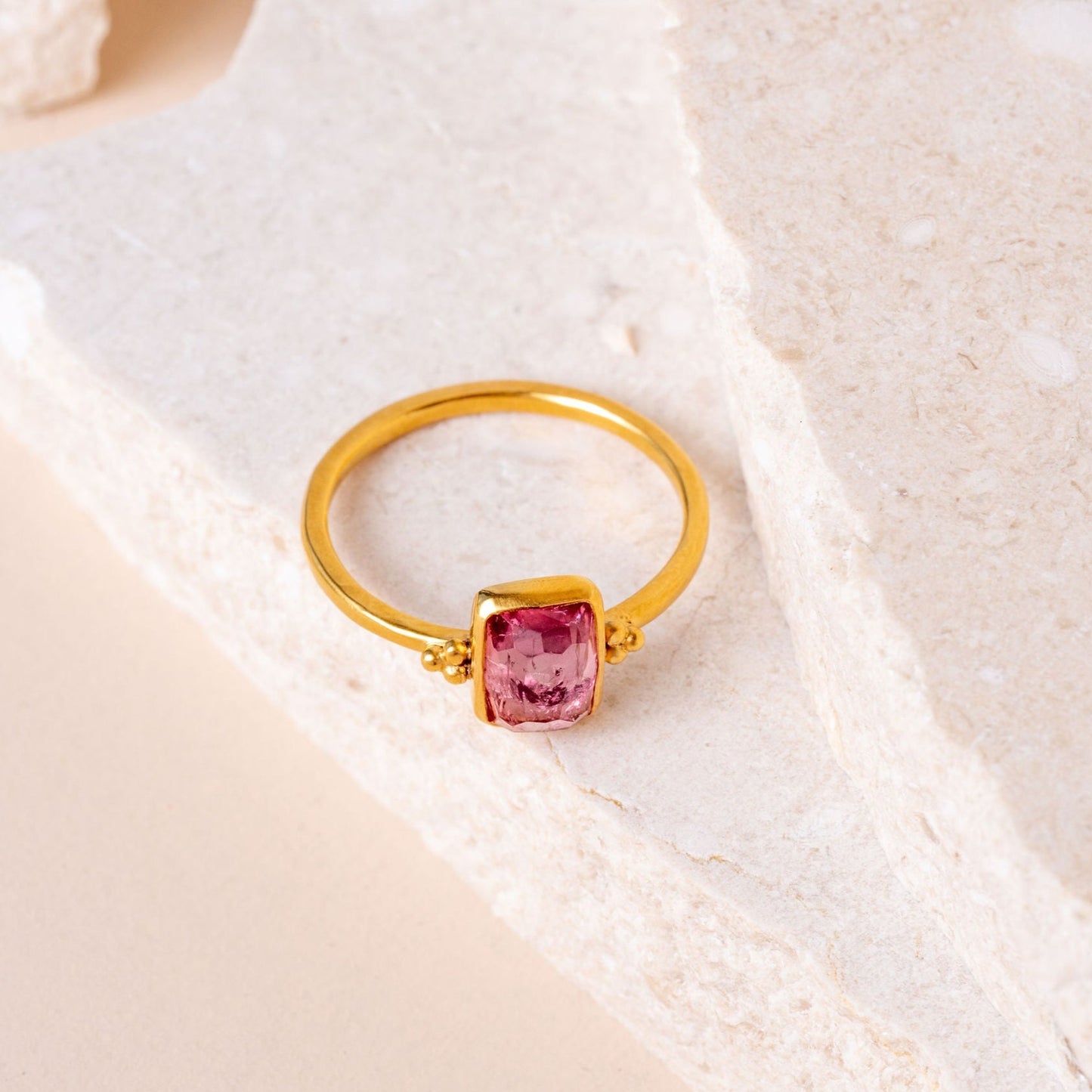 Handmade gold ring with delicate granulation framing a captivating pink tourmaline gemstone.