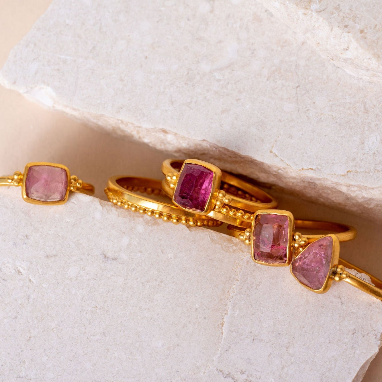 Collection of artisanal gold rings adorned with various hand-cut pink tourmalines, each featuring intricate granulation details