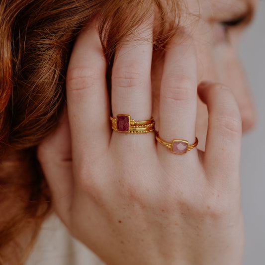 Stacked gold rings featuring captivating pink rose-cut tourmalines and granulation details.
