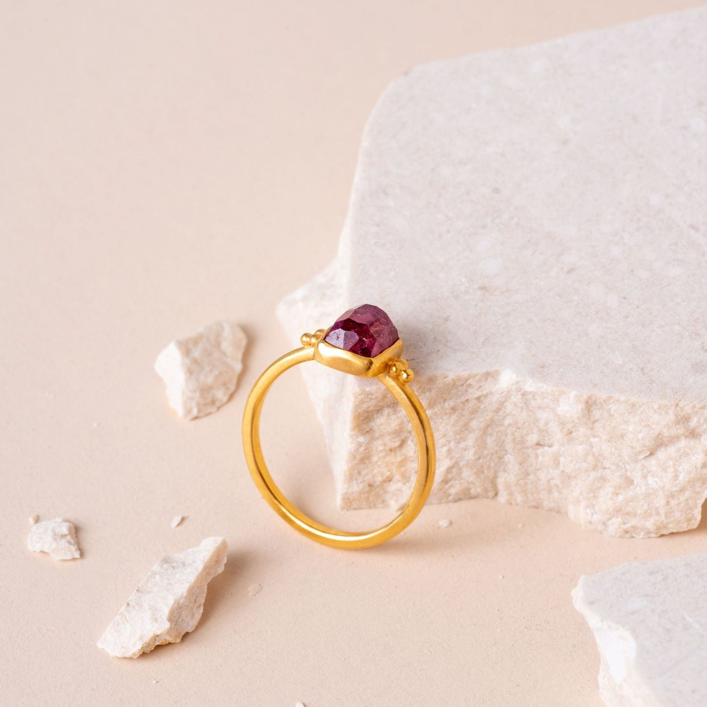 Elegantly crafted gold vermeil ring showcasing a hand-cut pink tourmaline, complemented by intricate granulation detailing on either side.
