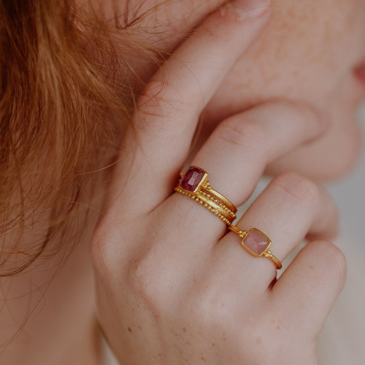 Graceful stack of gold rings, adorned with a stunning pink rose-cut tourmaline, creating a unique look.